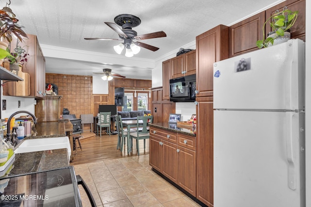 614 Bay Blvd, Bayville, NJ 08721 - kitchen with black appliances, a ceiling fan, dark stone counters, brown cabinets, and ornamental molding