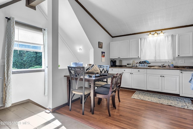 614 Bay Blvd, Bayville, NJ 08721 - kitchen with dark countertops, white cabinetry, vaulted ceiling, ornamental molding, and light wood-style flooring