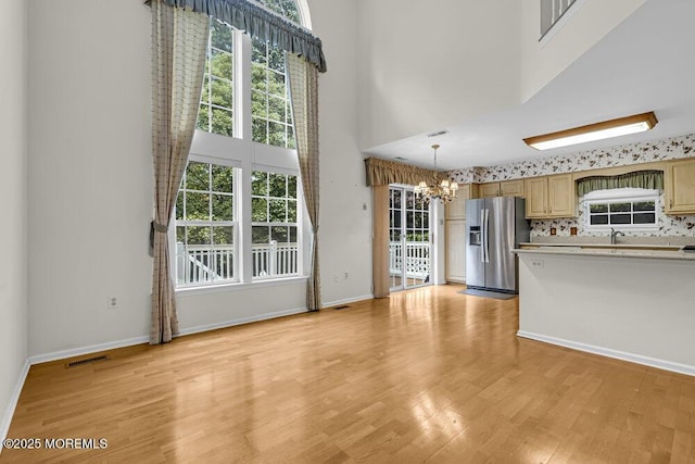 106 Tarpon Dr, Sea Girt, NJ 08750 - unfurnished living room with a chandelier, a high ceiling, light wood-style flooring, and plenty of natural light