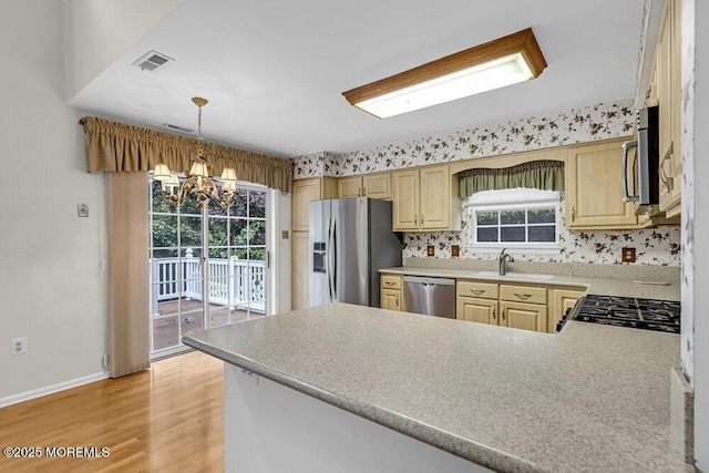 106 Tarpon Dr, Sea Girt, NJ 08750 - kitchen with appliances with stainless steel finishes, a chandelier, a peninsula, light countertops, and light wood-style floors
