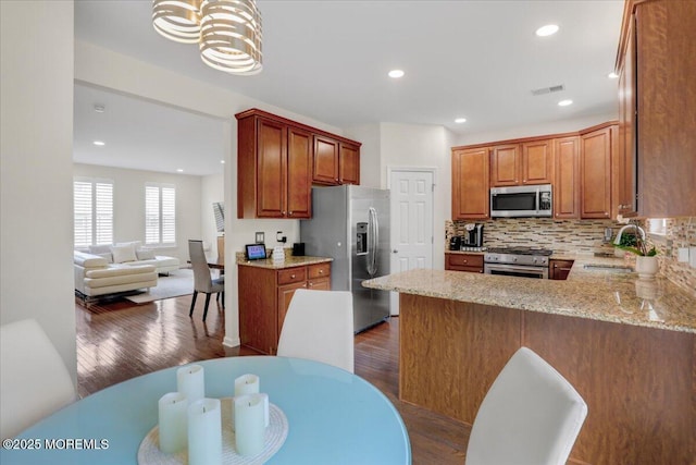 108 Warbler Way, Freehold, NJ 07728 - kitchen featuring stainless steel appliances, dark wood-style floors, tasteful backsplash, a peninsula, and light stone counters