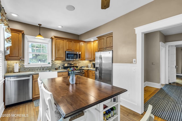 28 Broadway Rd, Freehold, NJ 07728 - kitchen with stainless steel appliances, light wood finished floors, decorative backsplash, a wainscoted wall, and brown cabinetry