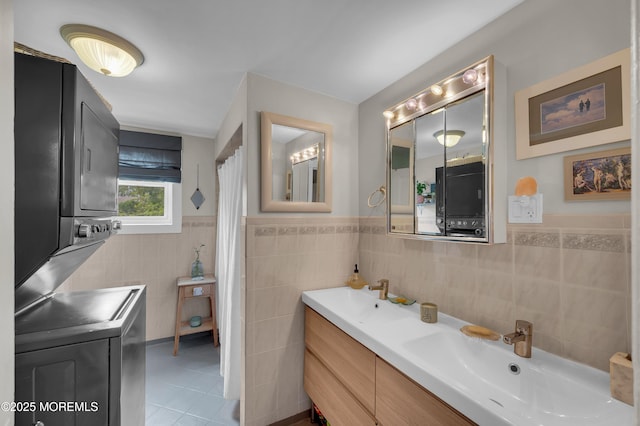 396 2nd Ave, Long Branch, NJ 07740 - full bath with stacked washing machine and dryer, tile walls, tile patterned flooring, double vanity, and a wainscoted wall