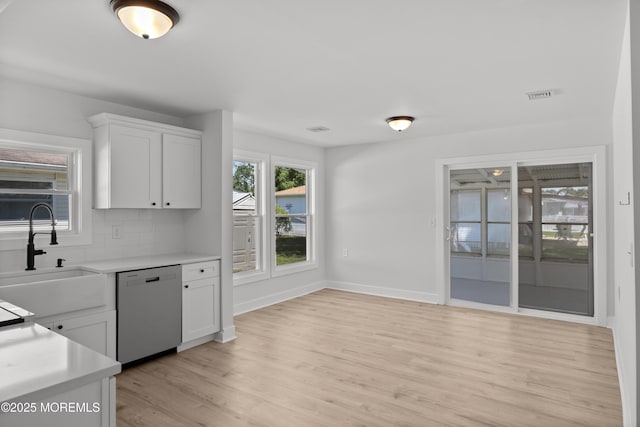 503 Jamaica Blvd, Toms River, NJ 08757 - kitchen with stainless steel dishwasher, light countertops, light wood-style flooring, white cabinetry, and backsplash