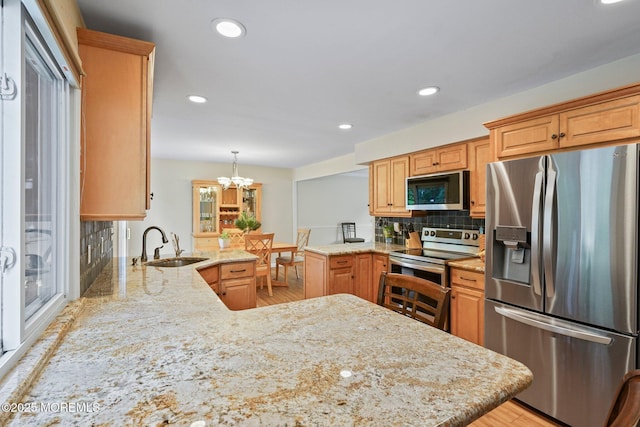 11 Hazelwood Ct, Howell, NJ 07731 - kitchen with appliances with stainless steel finishes, a peninsula, decorative backsplash, light stone counters, and light wood-style floors