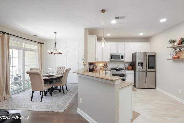 408 April Way, Middletown, NJ 07748 - kitchen with appliances with stainless steel finishes, a peninsula, white cabinetry, light stone counters, and plenty of natural light