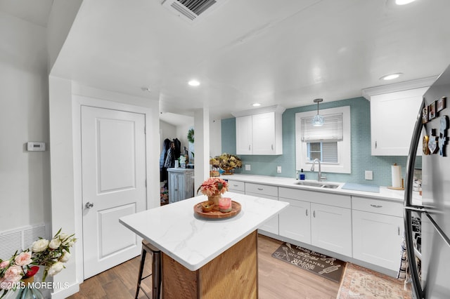 402 2nd Ave, Long Branch, NJ 07740 - kitchen featuring wood finished floors, a kitchen island, freestanding refrigerator, recessed lighting, and white cabinetry