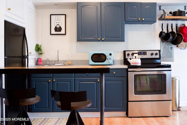 1730 Newman St, Belmar, NJ 07719 - kitchen with stainless steel range with electric stovetop, white microwave, blue cabinets, and tasteful backsplash