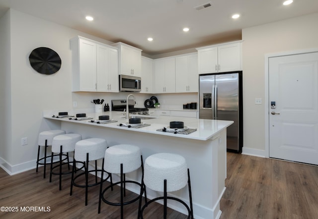 28202 Radford Ct, Monroe, NJ 08831 - kitchen featuring appliances with stainless steel finishes, a peninsula, a breakfast bar, white cabinets, and recessed lighting
