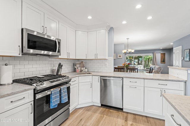 7 Steeple Chase Ct, Tinton Falls, NJ 07724 - kitchen with appliances with stainless steel finishes, light wood-type flooring, a chandelier, open floor plan, and tasteful backsplash