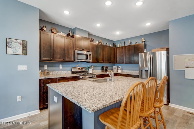 107 Sandpiper Ln, Little Egg Harbor, NJ 08087 - kitchen with stainless steel appliances, light wood-type flooring, a breakfast bar, dark brown cabinetry, and light stone counters