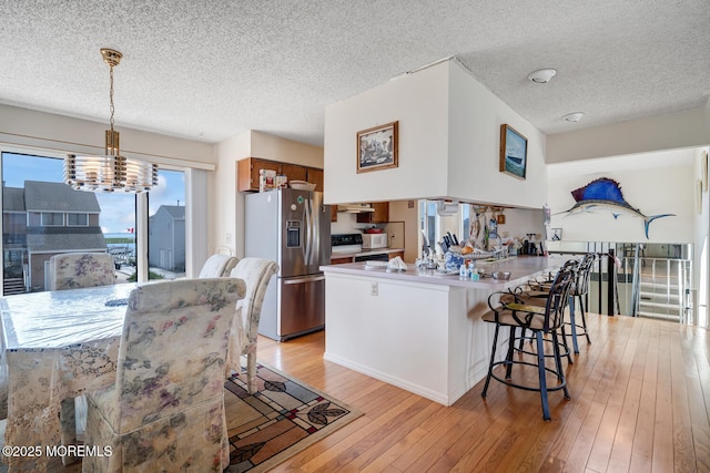 1856 Mill Creek Rd, Beach Haven West, NJ 08050 - kitchen featuring stainless steel fridge with ice dispenser, a textured ceiling, light wood-style floors, a chandelier, and a breakfast bar area