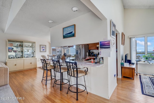1856 Mill Creek Rd, Beach Haven West, NJ 08050 - kitchen featuring stainless steel fridge with ice dispenser, a textured ceiling, light wood-style floors, a kitchen breakfast bar, and a high ceiling