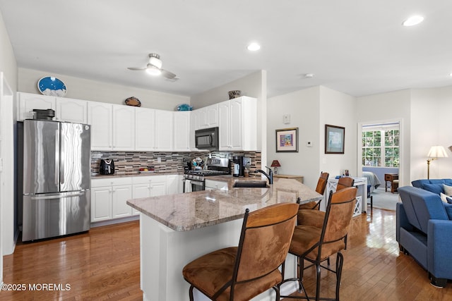 45 Marigold Ln, Little Egg Harbor, NJ 08087 - kitchen with stainless steel appliances, a peninsula, light stone counters, a breakfast bar, and hardwood / wood-style flooring