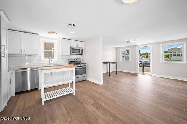 139 Seabreeze Ave, North Middletown, NJ 07748 - kitchen featuring appliances with stainless steel finishes, tasteful backsplash, wood finished floors, and white cabinetry