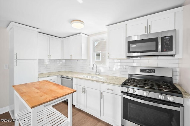 139 Seabreeze Ave, North Middletown, NJ 07748 - kitchen with stainless steel appliances, white cabinetry, decorative backsplash, light wood finished floors, and light stone countertops
