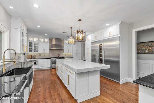 9 Withers Ln, Atlantic Highlands, NJ 07716 - kitchen with high quality appliances, wall chimney exhaust hood, dark stone counters, white cabinets, and recessed lighting