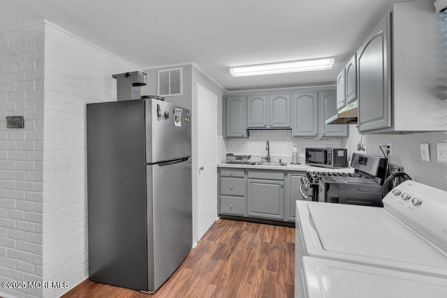 99 Roosevelt Cir E, Red Bank, NJ 07701 - kitchen featuring appliances with stainless steel finishes, gray cabinetry, washer / dryer, dark wood finished floors, and under cabinet range hood