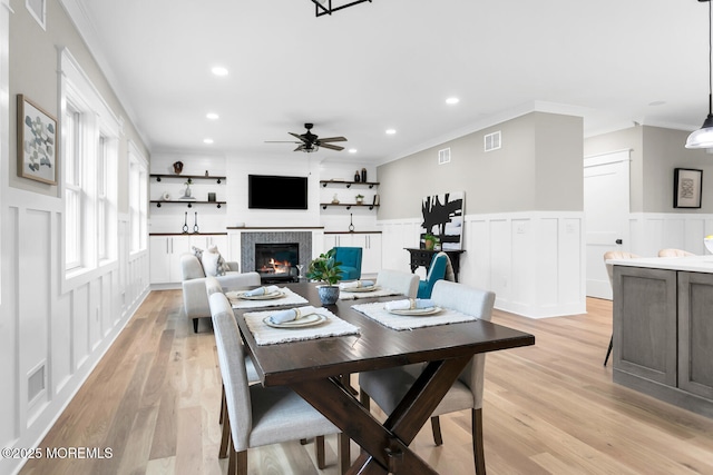 515 Atlantic Ave, Middletown, NJ 07748 - dining area with a decorative wall, crown molding, a ceiling fan, a tile fireplace, and light wood-style floors
