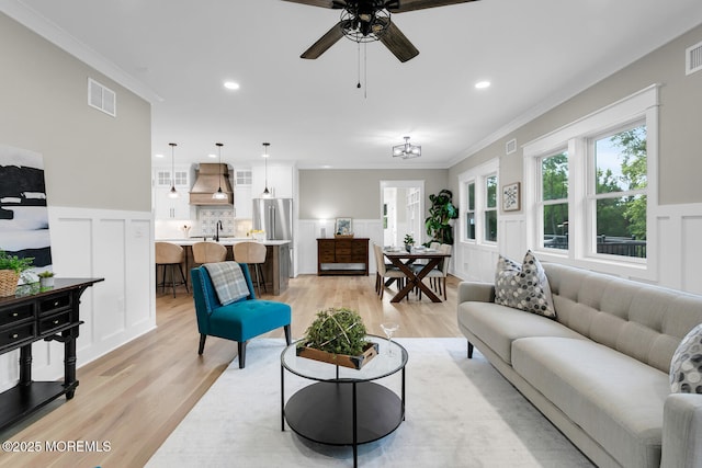 515 Atlantic Ave, Middletown, NJ 07748 - living area with light wood-style flooring, crown molding, a ceiling fan, a decorative wall, and a wainscoted wall