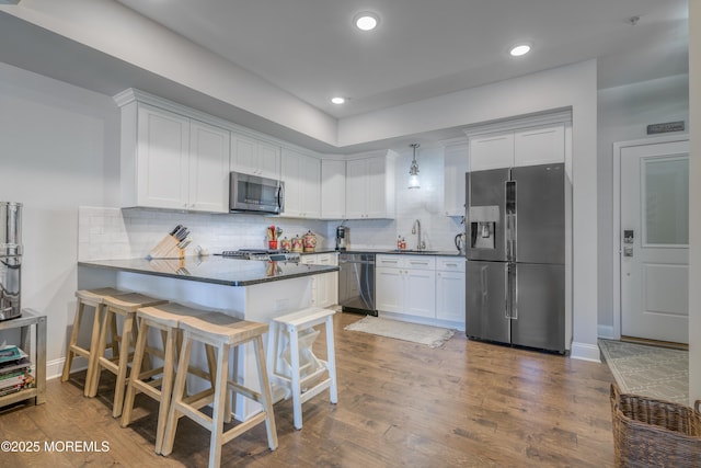26 9th Ave Unit 105, Ortley Beach, NJ 08751 - kitchen with appliances with stainless steel finishes, a peninsula, dark countertops, tasteful backsplash, and white cabinetry