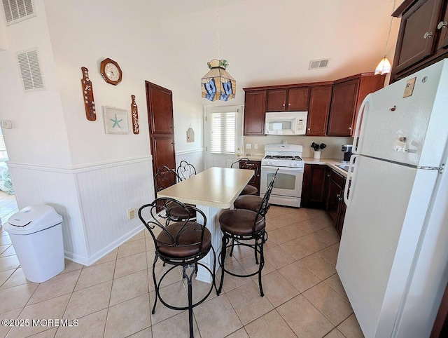 215 Harbor Dr, Lavallette, NJ 08735 - kitchen featuring white appliances, a wainscoted wall, light countertops, a breakfast bar, and light tile patterned floors