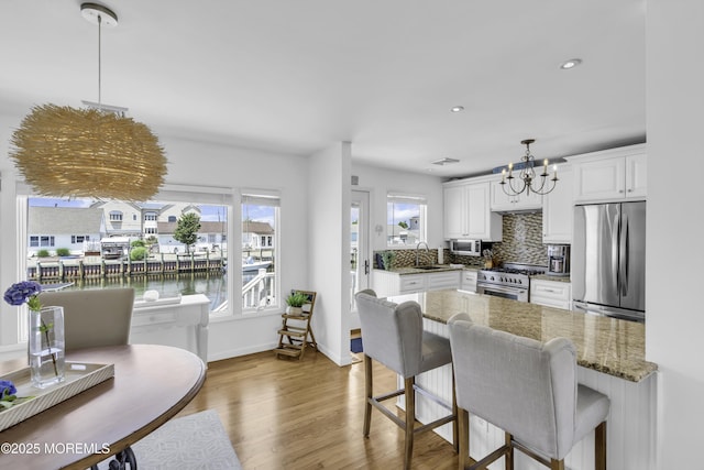 813 Tiller Dr, Forked River, NJ 08731 - kitchen featuring appliances with stainless steel finishes, a chandelier, white cabinets, wood finished floors, and backsplash