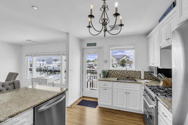 813 Tiller Dr, Forked River, NJ 08731 - kitchen with stainless steel appliances, a chandelier, white cabinetry, wood finished floors, and light stone countertops