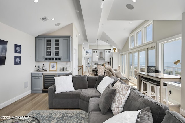 209 E 20th St, Long Beach Twp, NJ 08008 - living room featuring beverage cooler, a dry bar, light wood-style floors, vaulted ceiling, and plenty of natural light