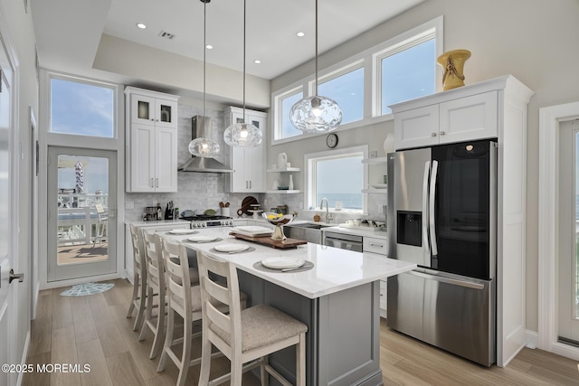 209 E 20th St, Long Beach Twp, NJ 08008 - kitchen with stainless steel appliances, wall chimney exhaust hood, white cabinetry, open shelves, and a kitchen breakfast bar