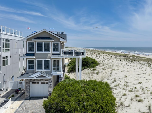 209 E 20th St, Long Beach Twp, NJ 08008 - view of front facade with a garage, view of water and beach, a standing seam roof, driveway, and a metal roof