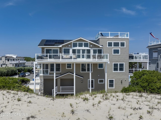209 E 20th St, Long Beach Twp, NJ 08008 - back of house featuring a balcony and roof mounted solar panels