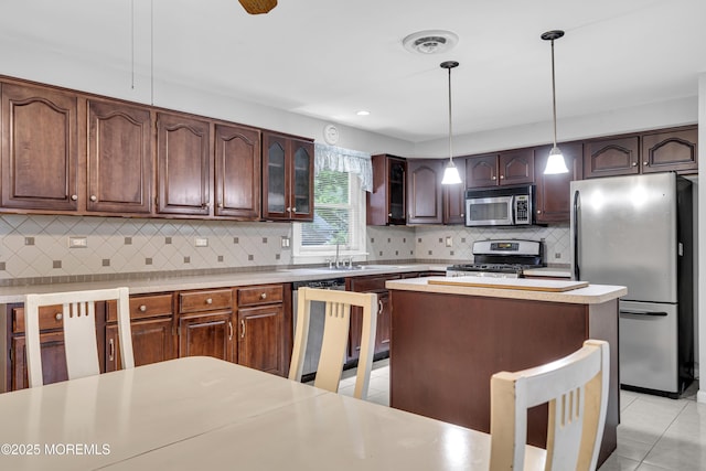 648 E Bayview Ave, Ocean Gate, NJ 08740 - kitchen with appliances with stainless steel finishes, light countertops, glass insert cabinets, light tile patterned floors, and decorative backsplash