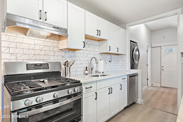 2905 Appleby Dr, Ocean Twp, NJ 07712 - kitchen featuring stainless steel appliances, under cabinet range hood, stacked washing machine and dryer, light countertops, and light wood-type flooring