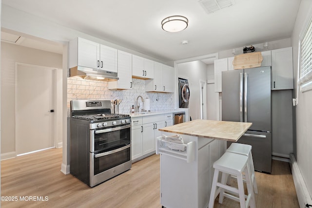 2905 Appleby Dr, Ocean Twp, NJ 07712 - kitchen featuring stainless steel appliances, under cabinet range hood, stacked washer and clothes dryer, backsplash, and baseboard heating