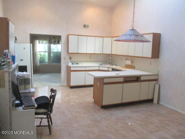 294 Marni Ln, Lakewood, NJ 08701 - kitchen with a peninsula, a high ceiling, light countertops, decorative light fixtures, and white cabinetry