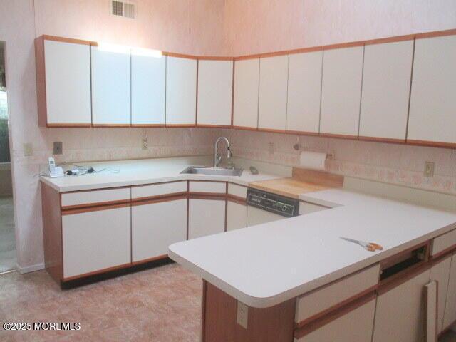 294 Marni Ln, Lakewood, NJ 08701 - kitchen featuring light countertops, white cabinetry, dishwashing machine, and a peninsula