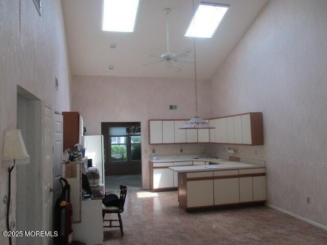 294 Marni Ln, Lakewood, NJ 08701 - kitchen with high vaulted ceiling, a peninsula, light countertops, white cabinets, and ceiling fan