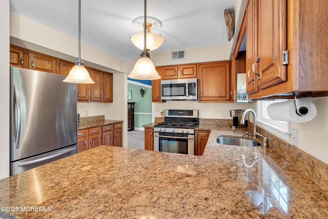 627 Meadow Run, Brick, NJ 08724 - kitchen with stainless steel appliances, brown cabinetry, light stone countertops, and pendant lighting