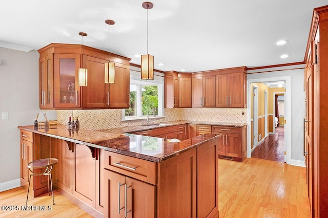 6 Opatut Ct, Morganville, NJ 07751 - kitchen featuring a peninsula, brown cabinets, ornamental molding, dark stone counters, and light wood-style flooring
