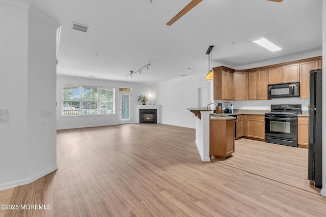 215 Sloan Ct, Matawan, NJ 07747 - kitchen with black appliances, open floor plan, a peninsula, light wood finished floors, and a glass covered fireplace
