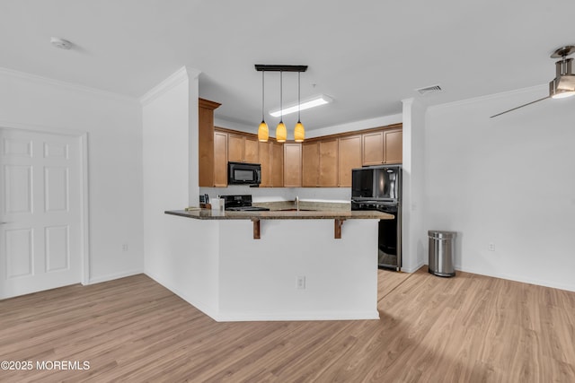 215 Sloan Ct, Matawan, NJ 07747 - kitchen with black appliances, a kitchen bar, dark stone countertops, light wood finished floors, and crown molding