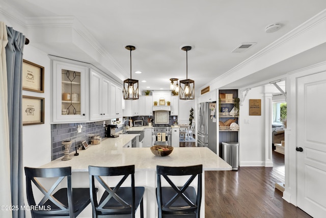 141 Twin Rivers Dr, Toms River, NJ 08753 - kitchen with stainless steel appliances, a peninsula, decorative backsplash, white cabinets, and ornamental molding