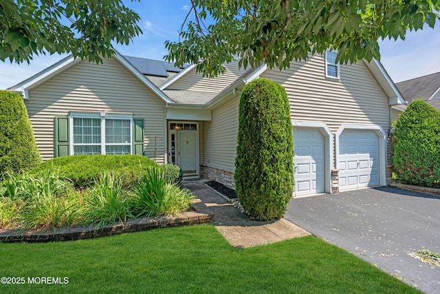 252 Enclave Blvd, Lakewood, NJ 08701 - view of front of property featuring asphalt driveway, solar panels, a front lawn, an attached garage, and stone siding