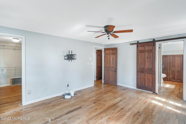 215 Parkertown Dr, Little Egg Harbor, NJ 08087 - unfurnished bedroom with wood finished floors, a barn door, a closet, a walk in closet, and a ceiling fan