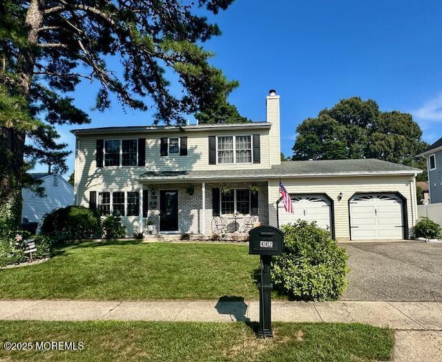 442 Mamie Dr, Brick, NJ 08723 - view of front facade with an attached garage, a chimney, asphalt driveway, a front lawn, and a porch
