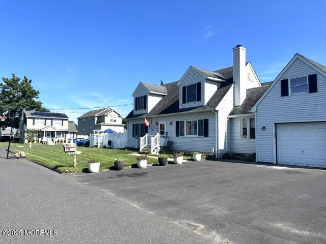 2711 2nd Ave, Toms River, NJ 08753 - new england style home with a chimney, an attached garage, a front yard, a residential view, and driveway