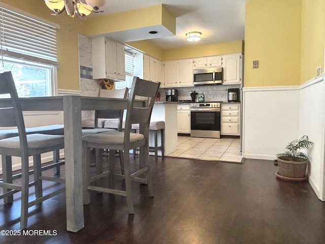 2711 2nd Ave, Toms River, NJ 08753 - kitchen featuring appliances with stainless steel finishes, a wainscoted wall, a chandelier, light wood-type flooring, and healthy amount of natural light