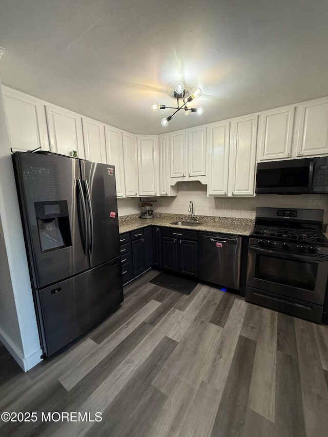 153 Schooner Ave, Barnegat, NJ 08005 - kitchen with black appliances, white cabinetry, a chandelier, and light stone counters