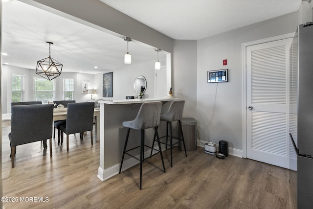 165 Tulip Ln, Freehold, NJ 07728 - kitchen with wood finished floors, a breakfast bar area, freestanding refrigerator, a chandelier, and pendant lighting